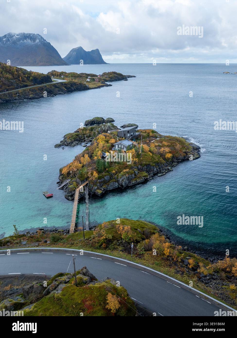 Blick aus der Vogelperspektive auf das Resort Hamn i Senja auf einer kleinen Insel mit Herbstlaub, türkisfarbenem Wasser und zerklüfteten Bergen in Skaland, Troms, Norwegen. Stockfoto