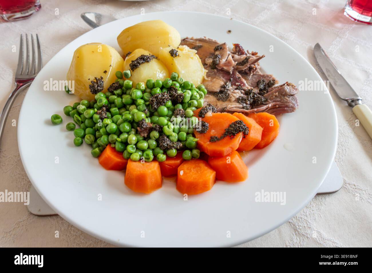 Ein traditionelles britisches Abendessen mit hausgemachtem Lammbraten mit Kartoffeln, Erbsen, Karotten und Minzsauce Stockfoto