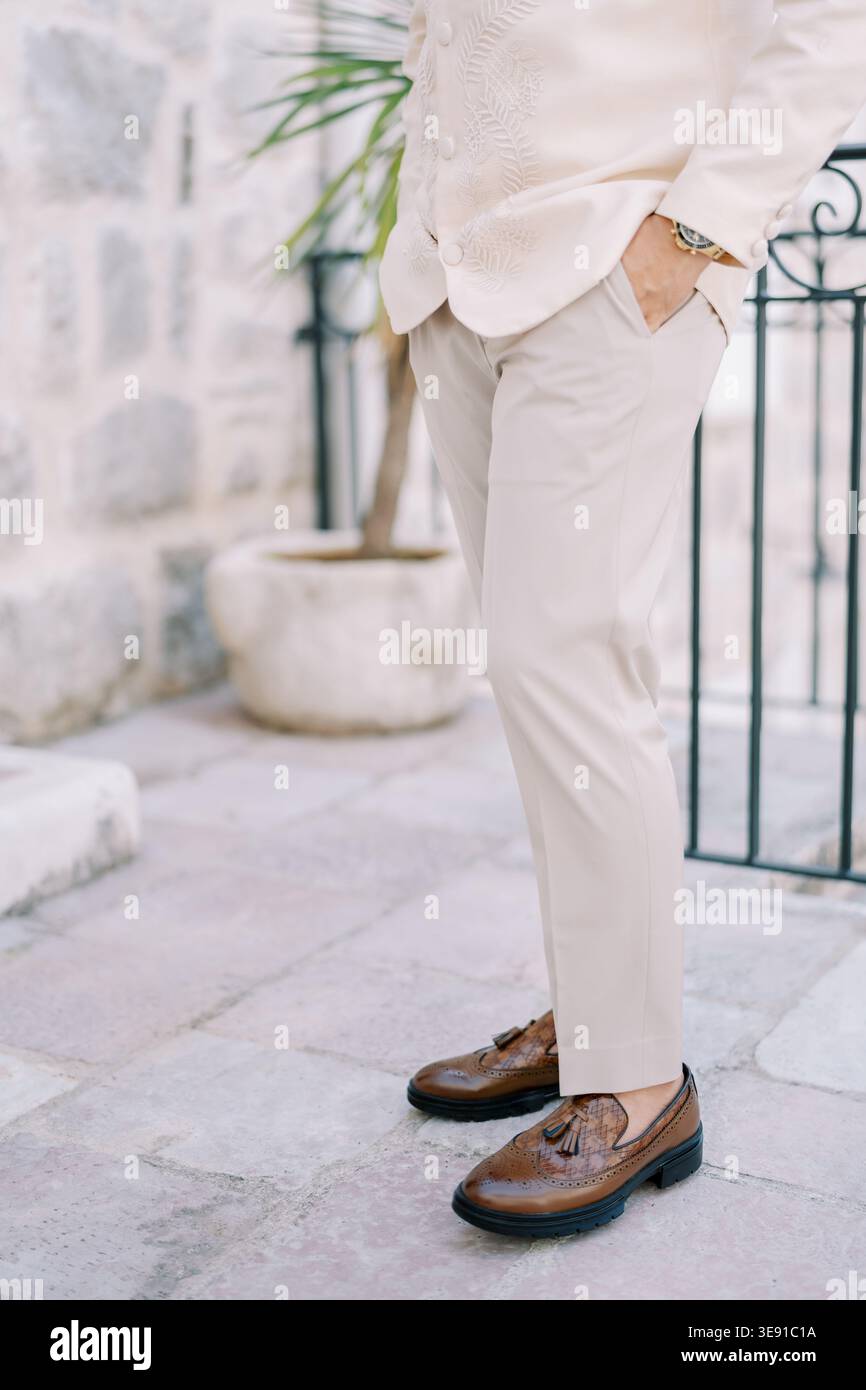 Eleganter Mann mit abgekürzten Hosen und Loafern in heller und dekorativer Umgebung im Freien Stockfoto