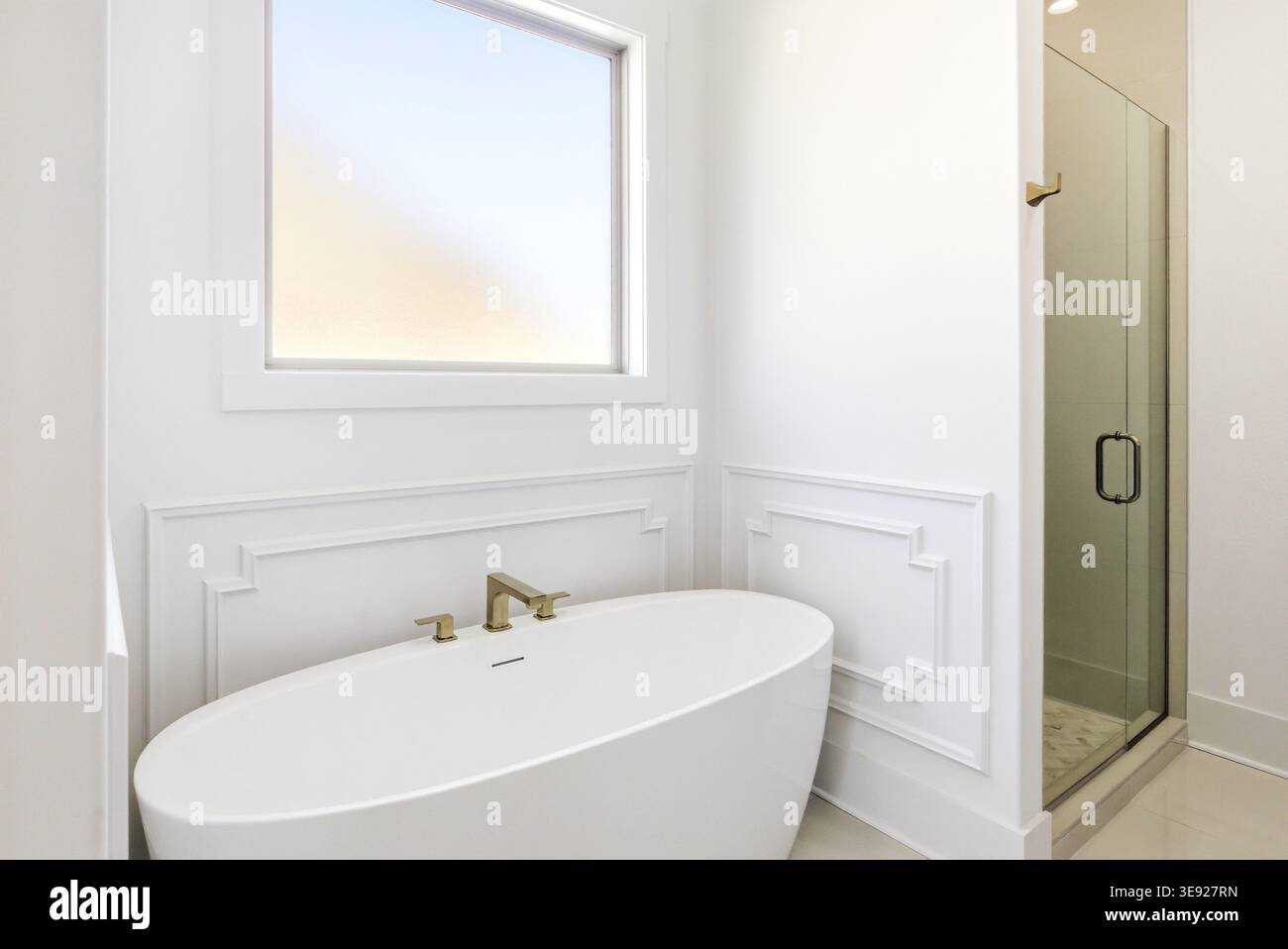 Sauberes Badezimmer mit Badewanne und Dusche in einem neu gebauten Haus mit neutralen Oberflächen. Stockfoto