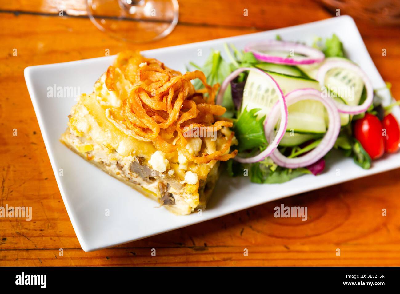 Quiche Lorraine-Scheibe mit gebratenen Zwiebeln und Gemüsesalat Stockfoto