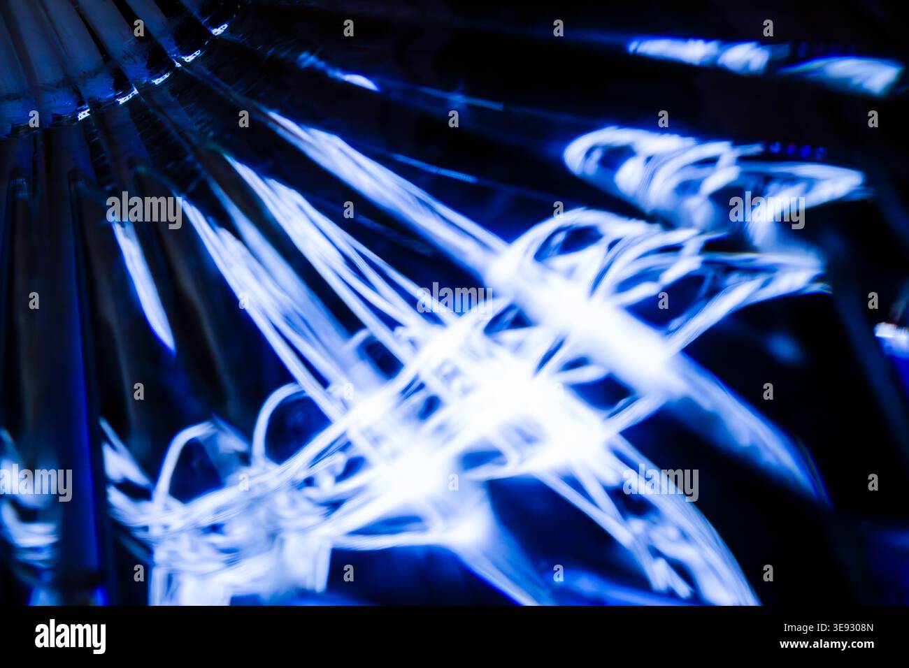 Verworrenes Netz von hellen blauen Lichtlinien, die auf einer komplexen kristallinen Glasoberfläche reflektiert werden Stockfoto