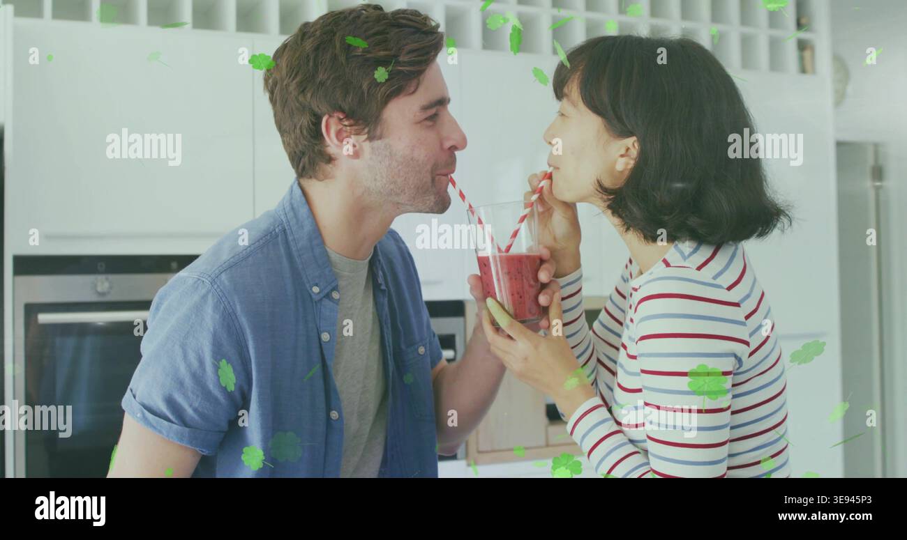 Ein Paar schlürft in der Küche Smoothie-Glas mit rot gestreiften Strohhalmen und gestreiftem Hemd Stockfoto