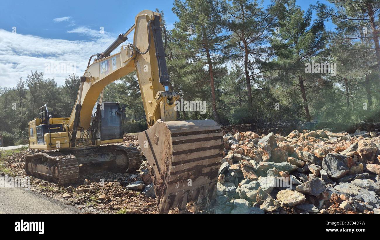 Gelber Hochleistungsbagger für Arbeiten auf felsigem Untergrund in einer Waldrodung Stockfoto