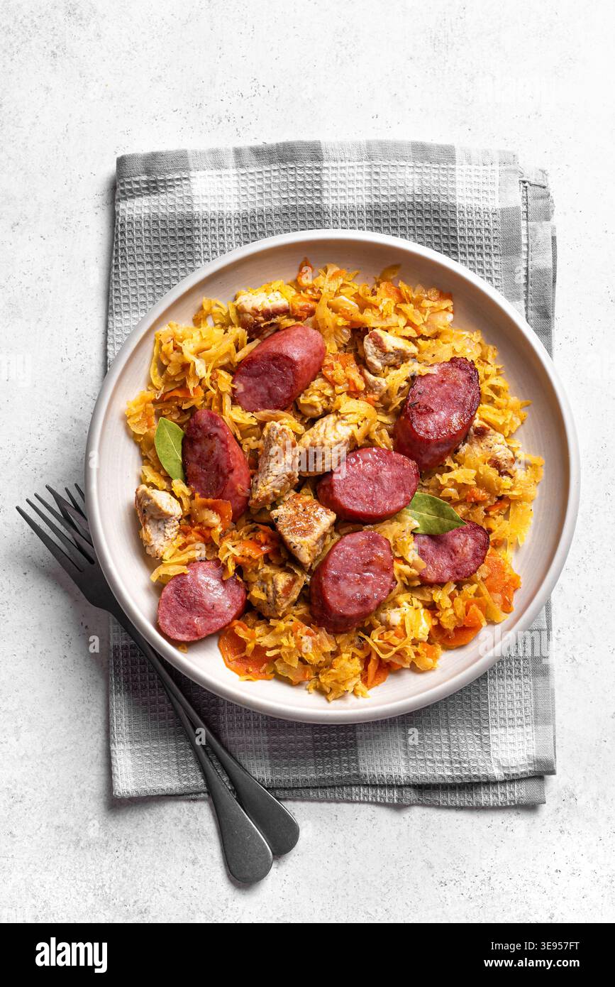 Traditionelle polnische Bigos-Mahlzeit oder Hunter's Stew mit Würstchen, Fleisch und Kohl in Keramikschale auf weißem Hintergrund, Blick von oben. Hausgemachtes geschmortes Sauerkr Stockfoto
