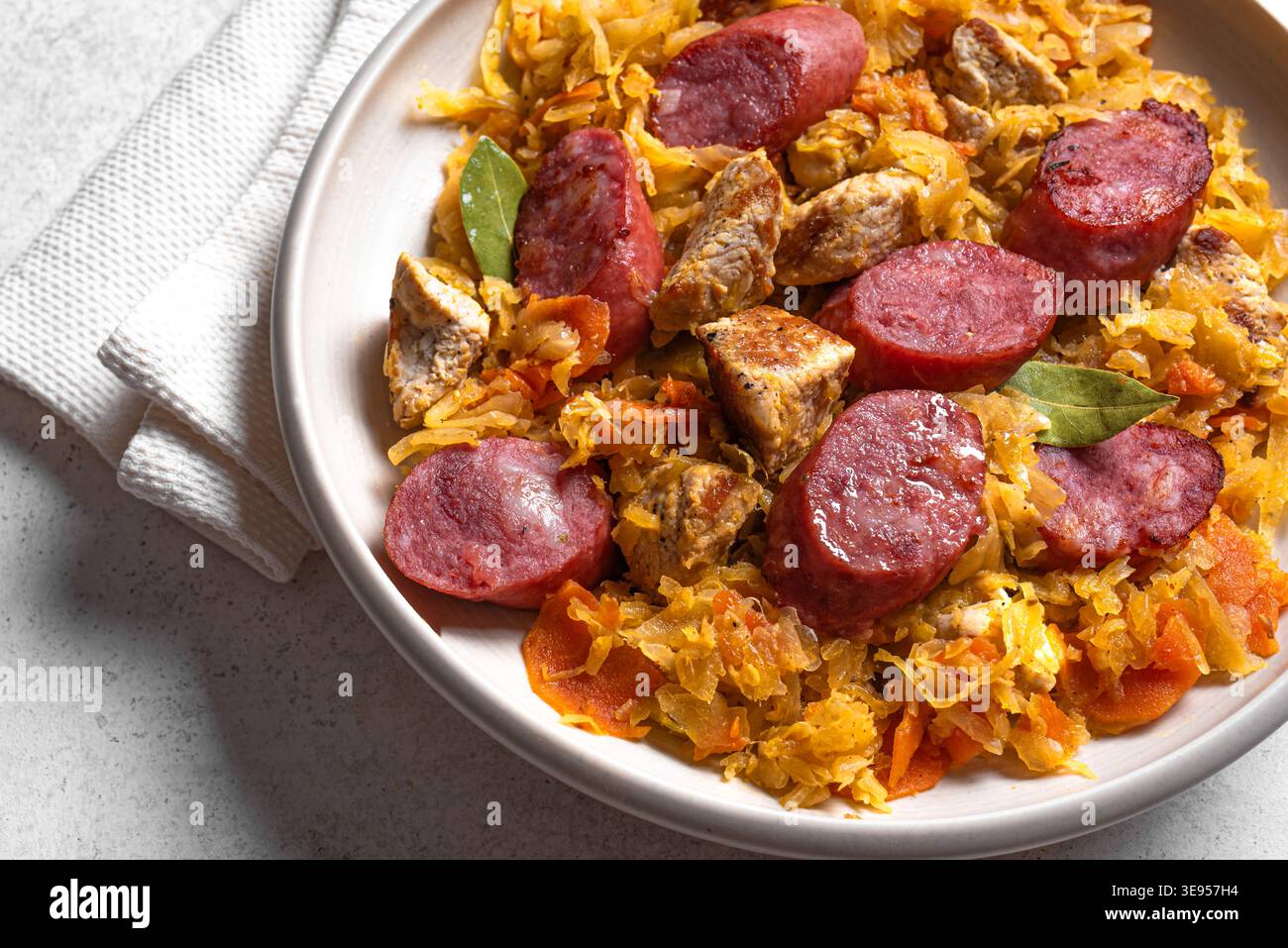 Traditionelle polnische Bigos-Mahlzeit oder Hunter's Stew mit Würstchen, Fleisch und gedünstetem Kohl in Keramikschale, detaillierte Ansicht von oben. Hausgemachtes geschmortes Sauerkraut Stockfoto