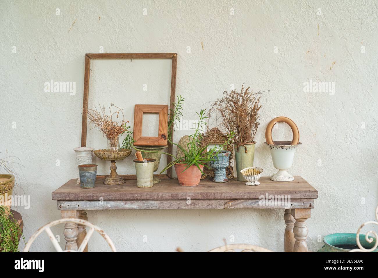 Antike Vintage-Objektsammlung mit Vase, Rahmen auf Holztisch und Gipswand im Wohnzimmer Stockfoto