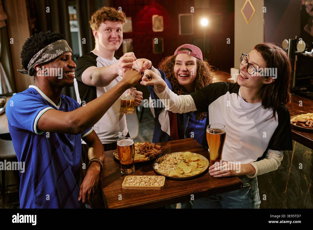 Verschiedene Erwachsene Freunde, die während der Game Night im Pub Fäuste schlagen Stockfoto