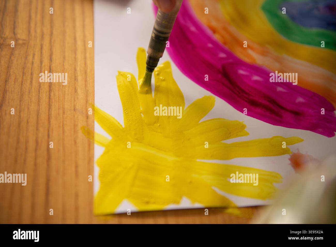 Ein Kind malt einen Regenbogen mit Farben. Nahaufnahme von Kinderhänden und Pinsel. Stockfoto