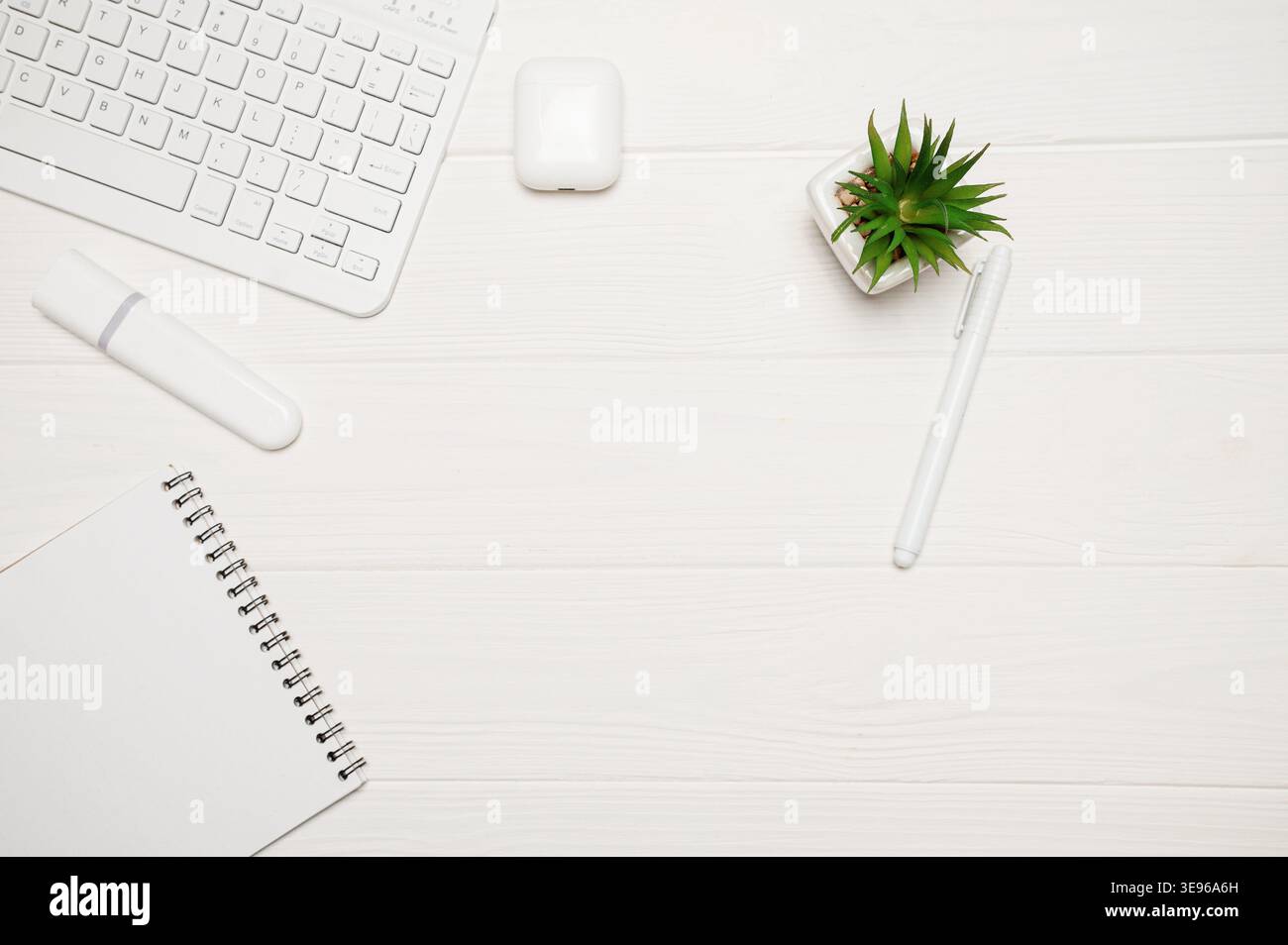 Minimaler Büroschreibtisch für Remote-Arbeiten mit weißer Tastatur, Anlage, Marker, Notebook und Ohrstöpsel auf Holz Stockfoto