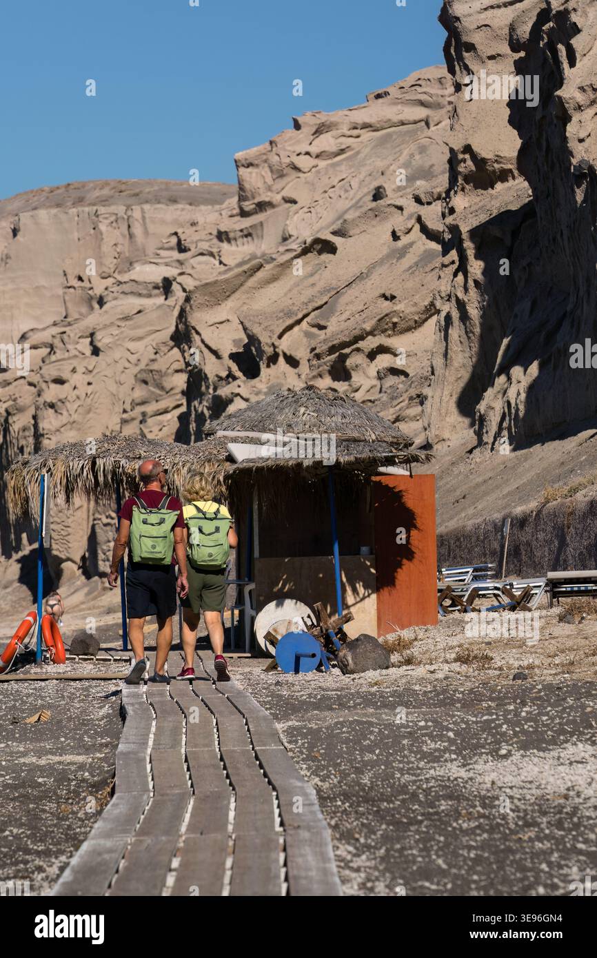 Santorini, Griechenland - 9. Oktober 2025 - Paar mit Rucksäcken spazieren auf der Promenade am Strand Vlychada Stockfoto