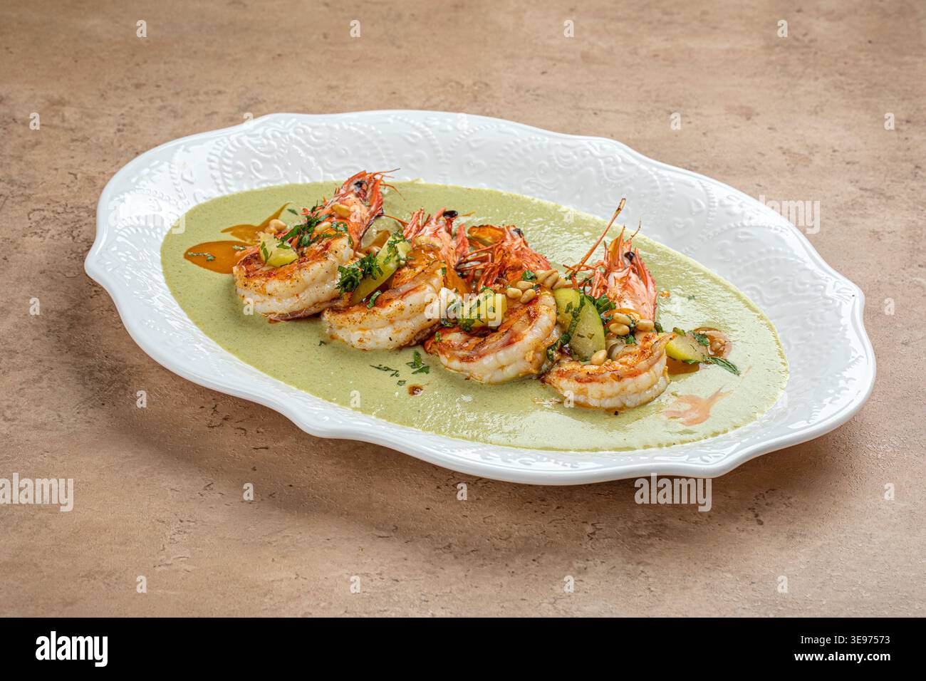 Gegrillte Garnelen mit grüner Sauce auf weißer Platte Stockfoto