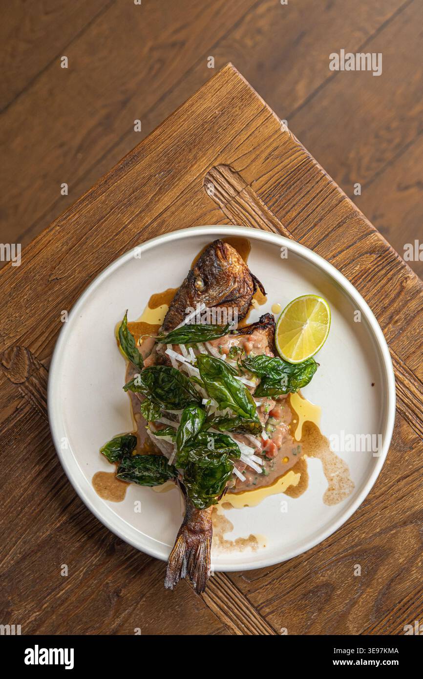 Gegrillter Fisch mit Kräutern und Limette auf Teller Stockfoto