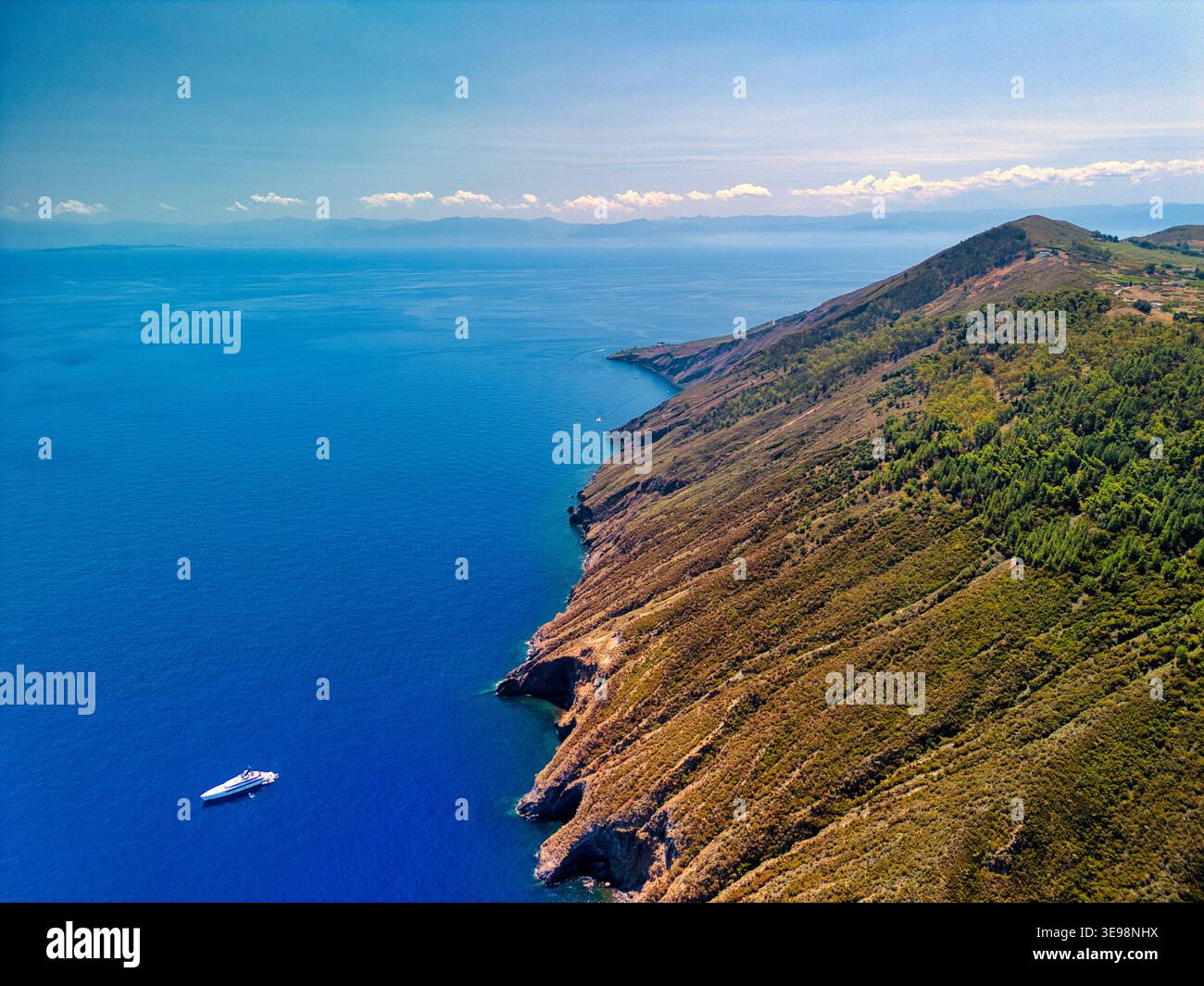 Blick aus der Vogelperspektive auf die zerklüftete Küste der Insel Vulcano mit steilen Klippen und einer weißen Yacht auf dem blauen Mittelmeer in Lipari, Sizilien, Italien. Stockfoto