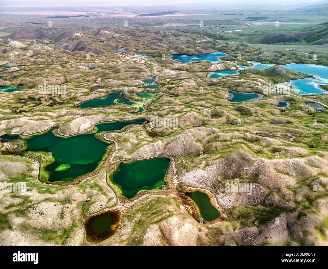 Aus der Vogelperspektive des Tulpar Lake und zahlreicher kleinerer alpiner Teiche, die über die sanften grünen Hügel und das zerklüftete Gelände im Alay District, Osh Region, verstreut sind. Stockfoto