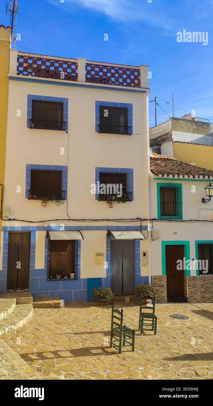 Malerische weiße und blaue Gebäude säumen eine sonnenbeschienene Kopfsteinpflasterstraße in Altea, Spanien, die Reisende zu einem entspannten Familienurlaub einladen Stockfoto
