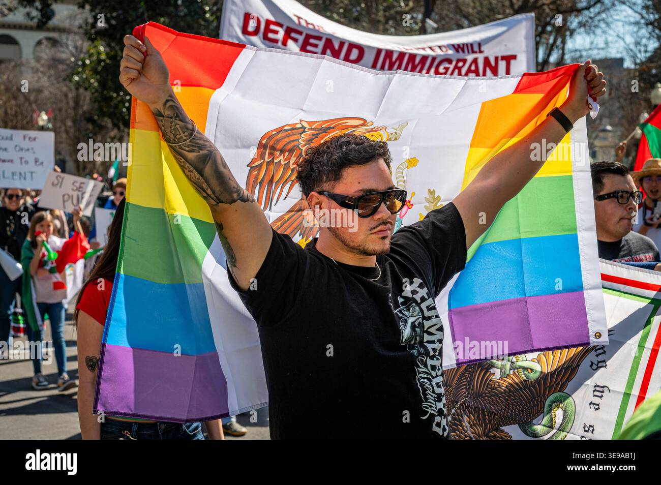 Ein Mann hält eine mexikanische Regenbogenflagge während eines einwanderungsfreundlichen marsches in Sacramento, Kalifornien, und unterstützt LGBTQ+ und Einwanderungsrechte. Stockfoto