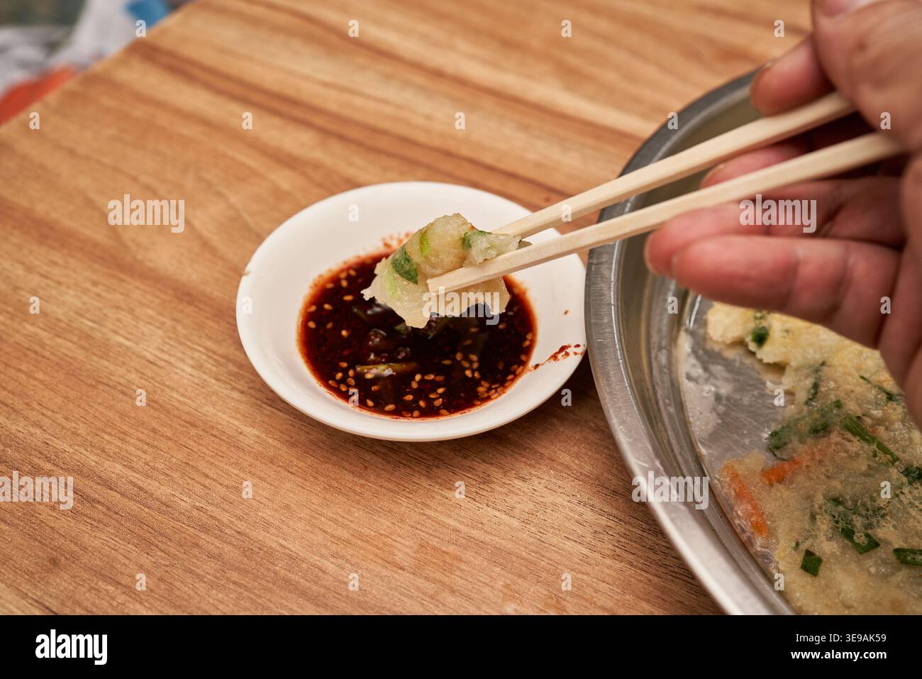 Gamjajeon, ein traditioneller Kartoffelpfannkuchen aus Gangwon-do, wird auf einem Stahlteller mit Sojasauce serviert. Es unterstreicht den herzhaften Geschmack der koreanischen lokalen Küche. Stockfoto