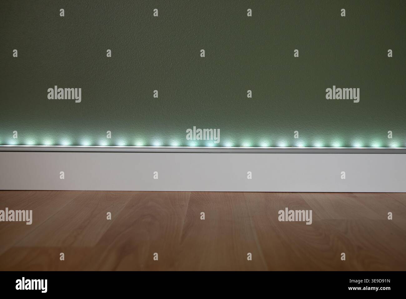 Eine LED-Leuchte mit Aluminiumprofil und einer diffusen Kunststoffabdeckung, die an der salbeigrünen Wand montiert ist. Stockfoto