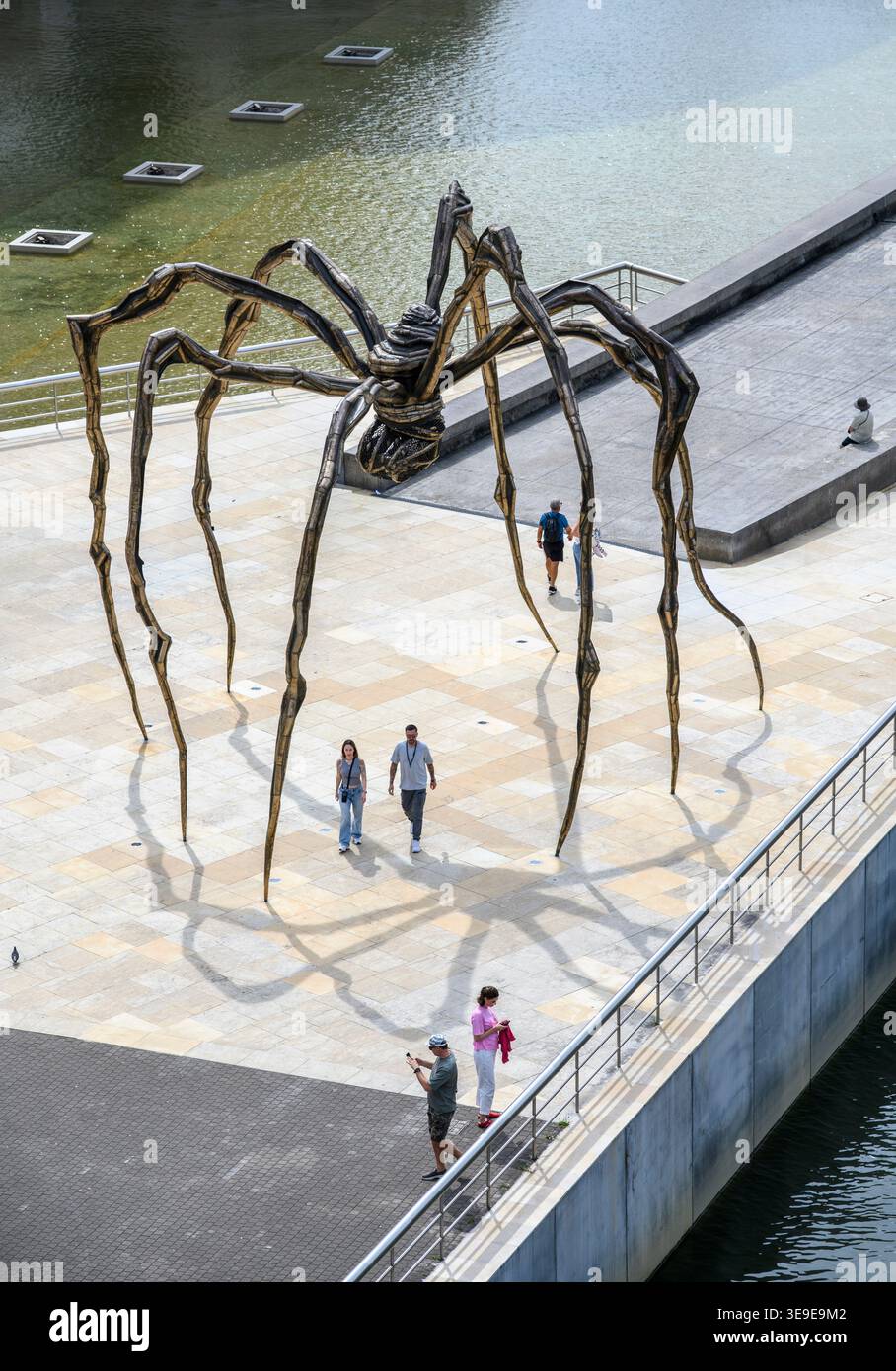 Besucher spazieren vorbei an der riesigen Spinnenskulptur „Maman“ der französischen Künstlerin Louise Bourgeois am Fluss im Guggenheim Museum, Bilbao, Biskaya, Ba Stockfoto