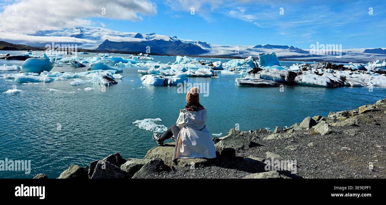 Eine Frau, die den Gletscher auf einem Felsen beobachtet - Smartphone-aufgenommenes Stockfoto
