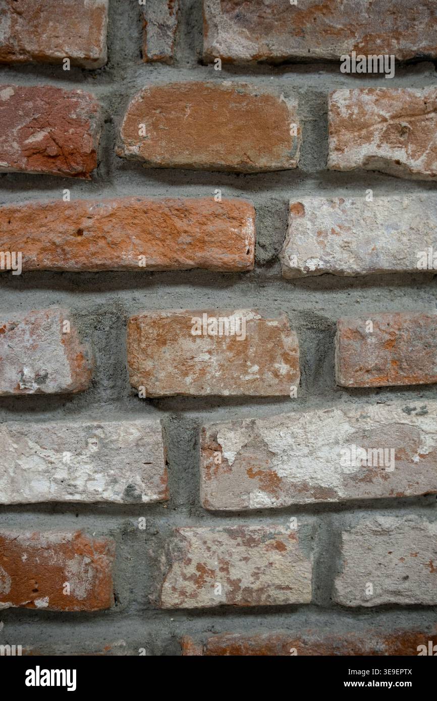 Strukturierte Ziegelwand mit einer Mischung aus roten und weißen Ziegeln mit sichtbaren Mörtelfugen und einem rustikalen Aussehen Stockfoto