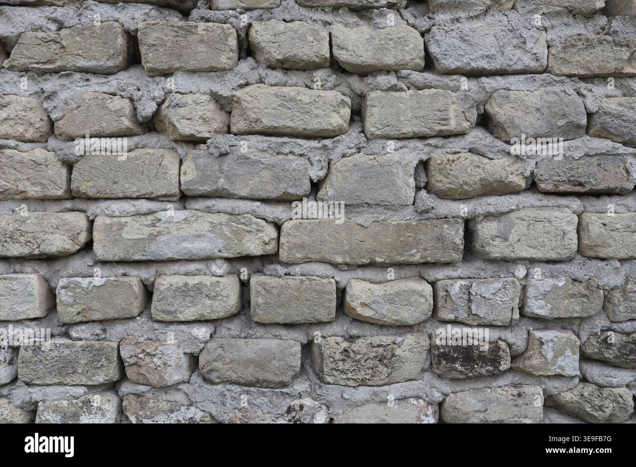 Eine alte graue Ziegelmauer. Zaun aus einem alten Haus. Stockfoto