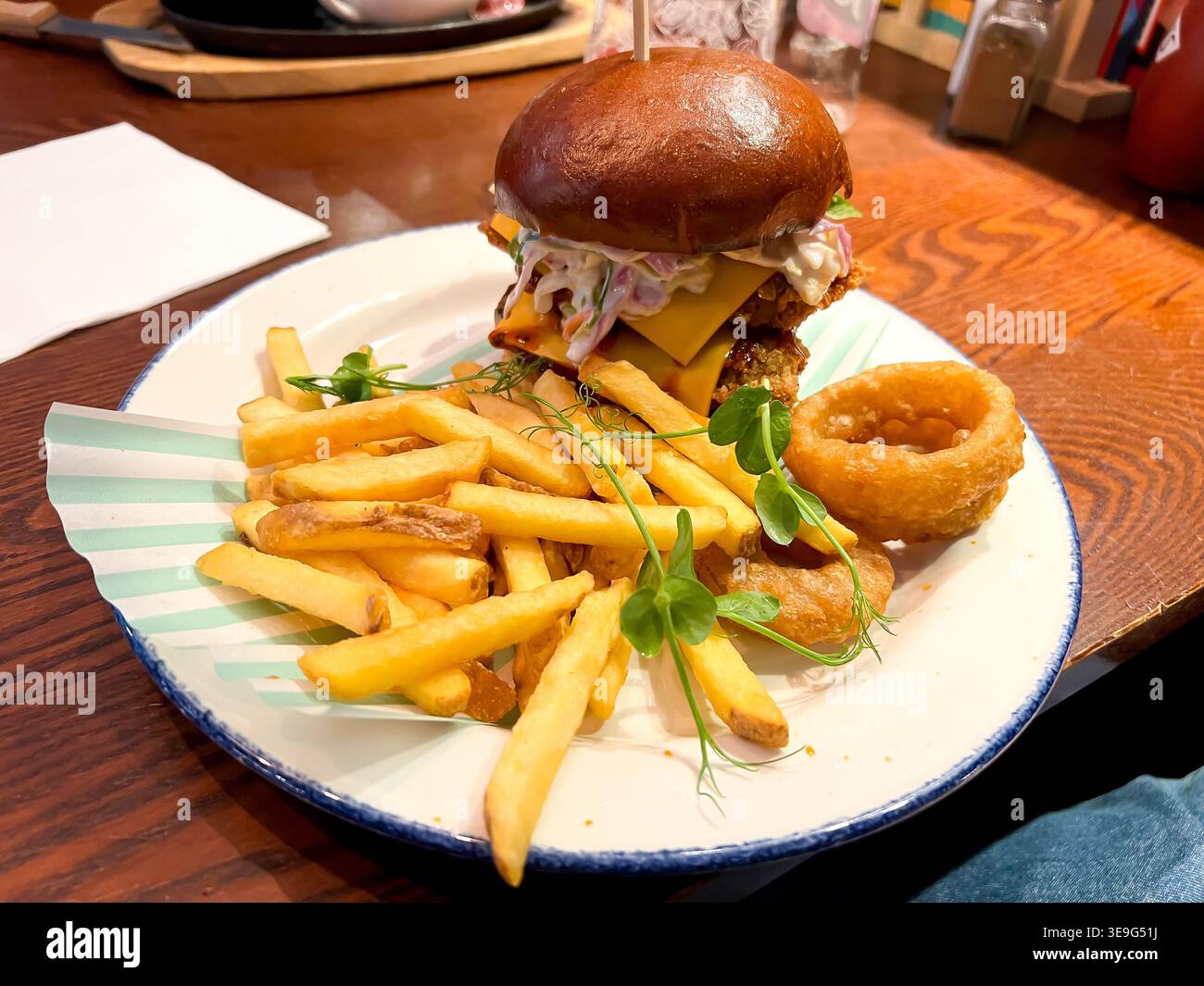 Ein Pub-Mittagessen mit Chicken Burger mit Pommes Frites und Zwiebelringen - Smartphone-aufgenommenes Stockfoto