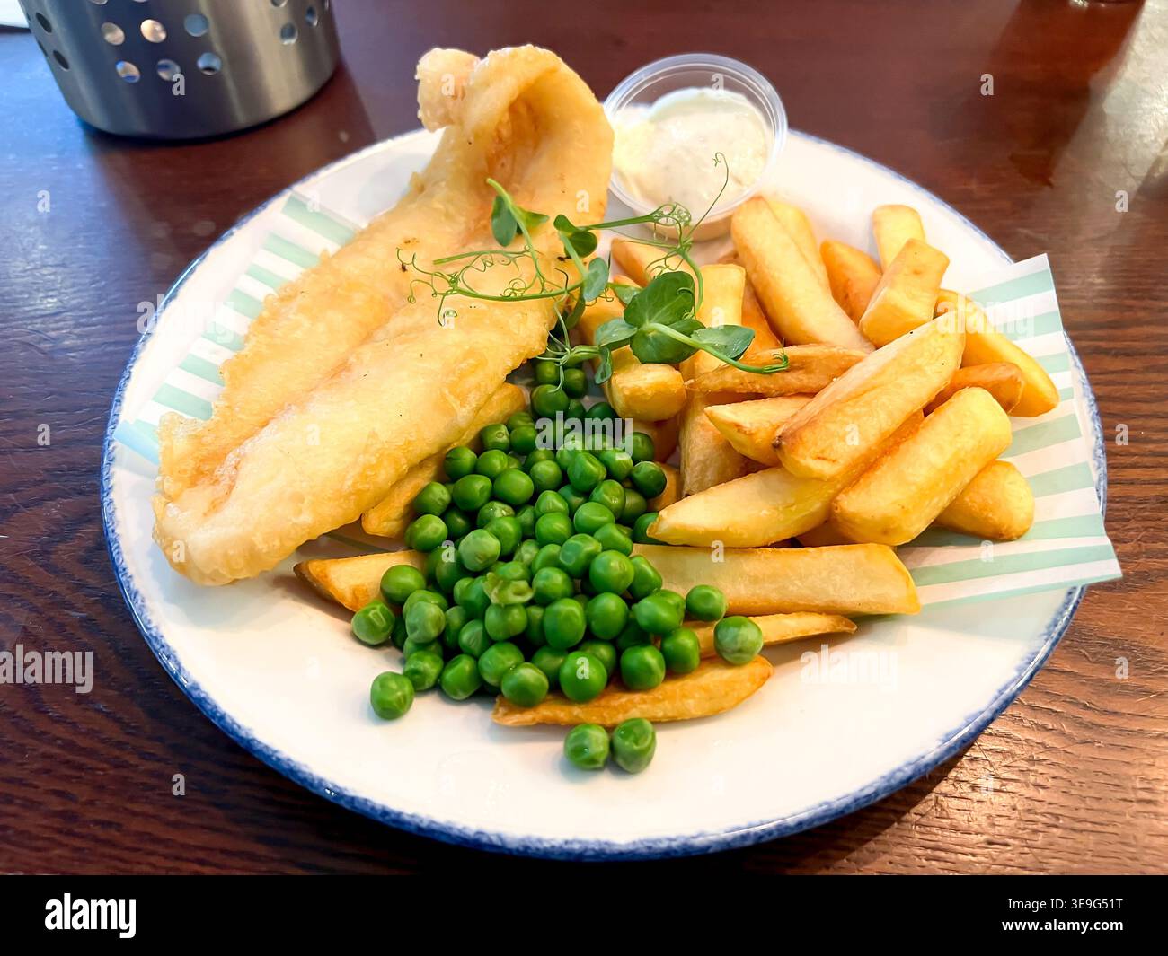 Fish and Chips mit Gartenerbsen, ein traditionelles britisches Pub-Mittagessen - Smartphone-aufgenommenes Stockfoto