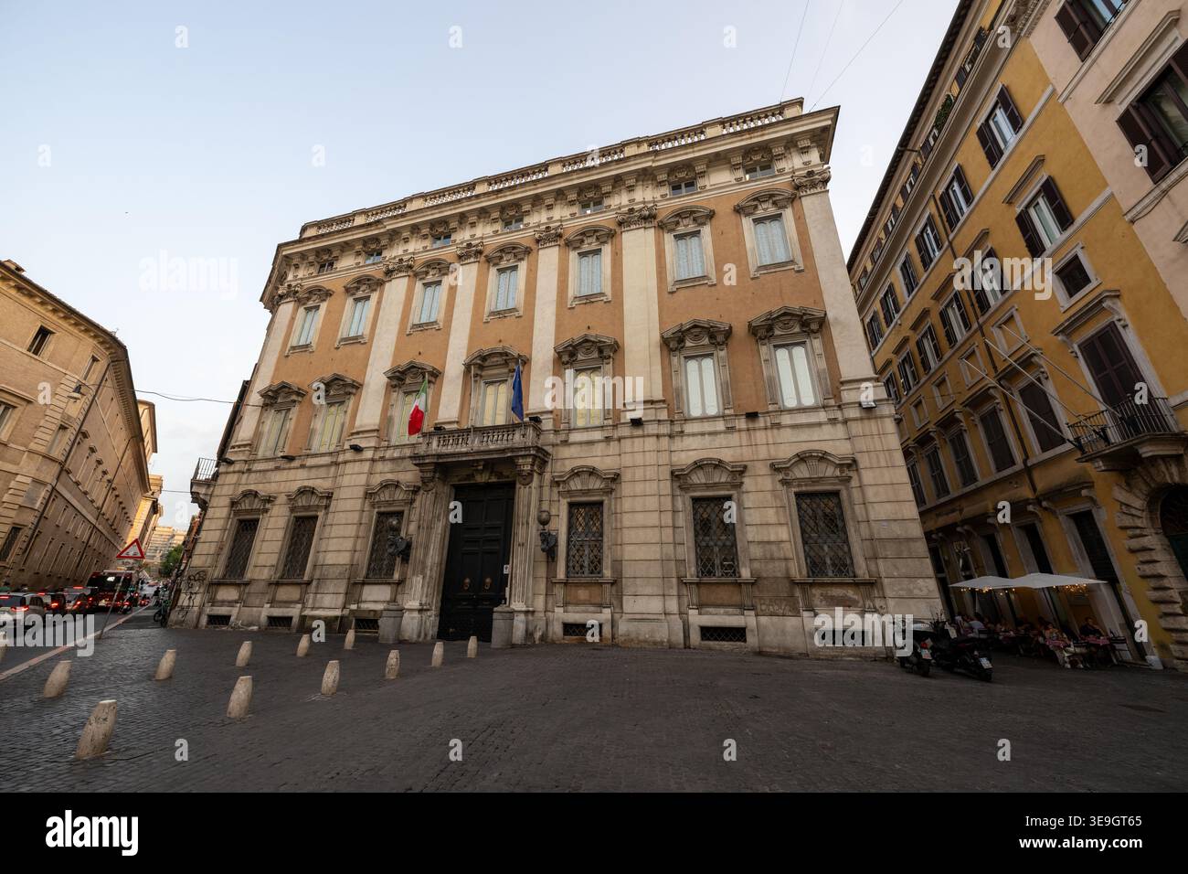 Fassade des Palazzo Cenci-Bolognetti in Rom, mit rustikalem Stein im Erdgeschoss, italienischer Flagge und Fensterläden in warmen Farben gehaltenen palazzo in der Abenddämmerung. Stockfoto