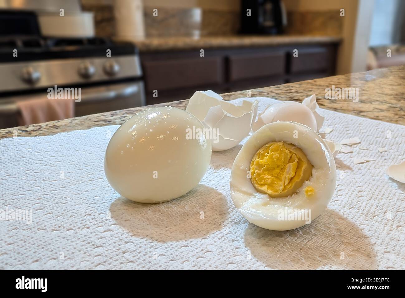 Hart gekochte Eier auf der Küchentheke mit geschälter Schale und teilweise gegessen Ei mit Eigelb Stockfoto