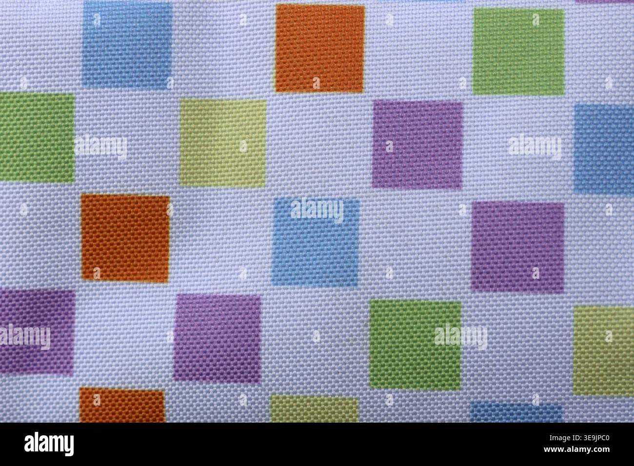 Lebendiges mehrfarbiges Schachbrettmuster auf strukturiertem weißem Canvas-Stoff mit erhöhten Webquadraten in Blau, Orange, Grün, Lila und Gelb Stockfoto