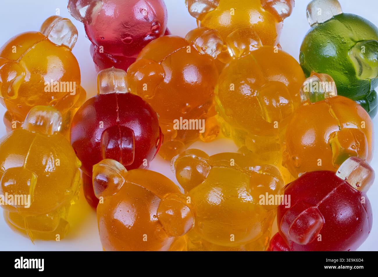 Verstreute fruchtige Marmelade-Bärenbonbons auf sauberem weißem Hintergrund, lässige Party-Atmosphäre mit gemischten Farben und sanften Reflexen, Gefühl von verspieltem Überfluss Stockfoto