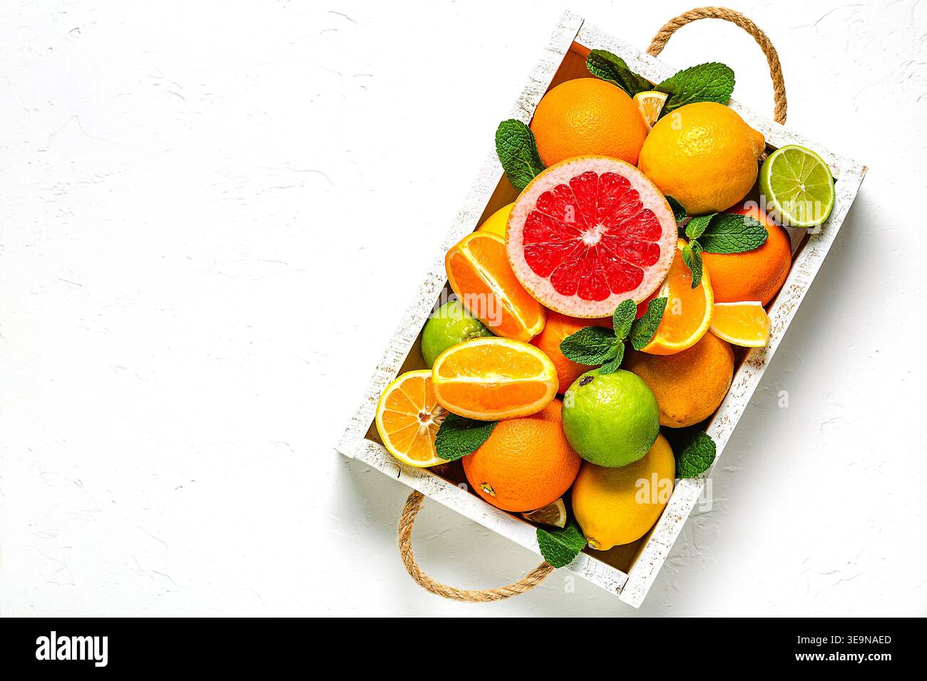 Frische Zitrusfrüchte mit Blättern: Zitronen, Orangen, Mandarinen, Grapefruit, Limette in Holzkiste, Draufsicht. Stockfoto