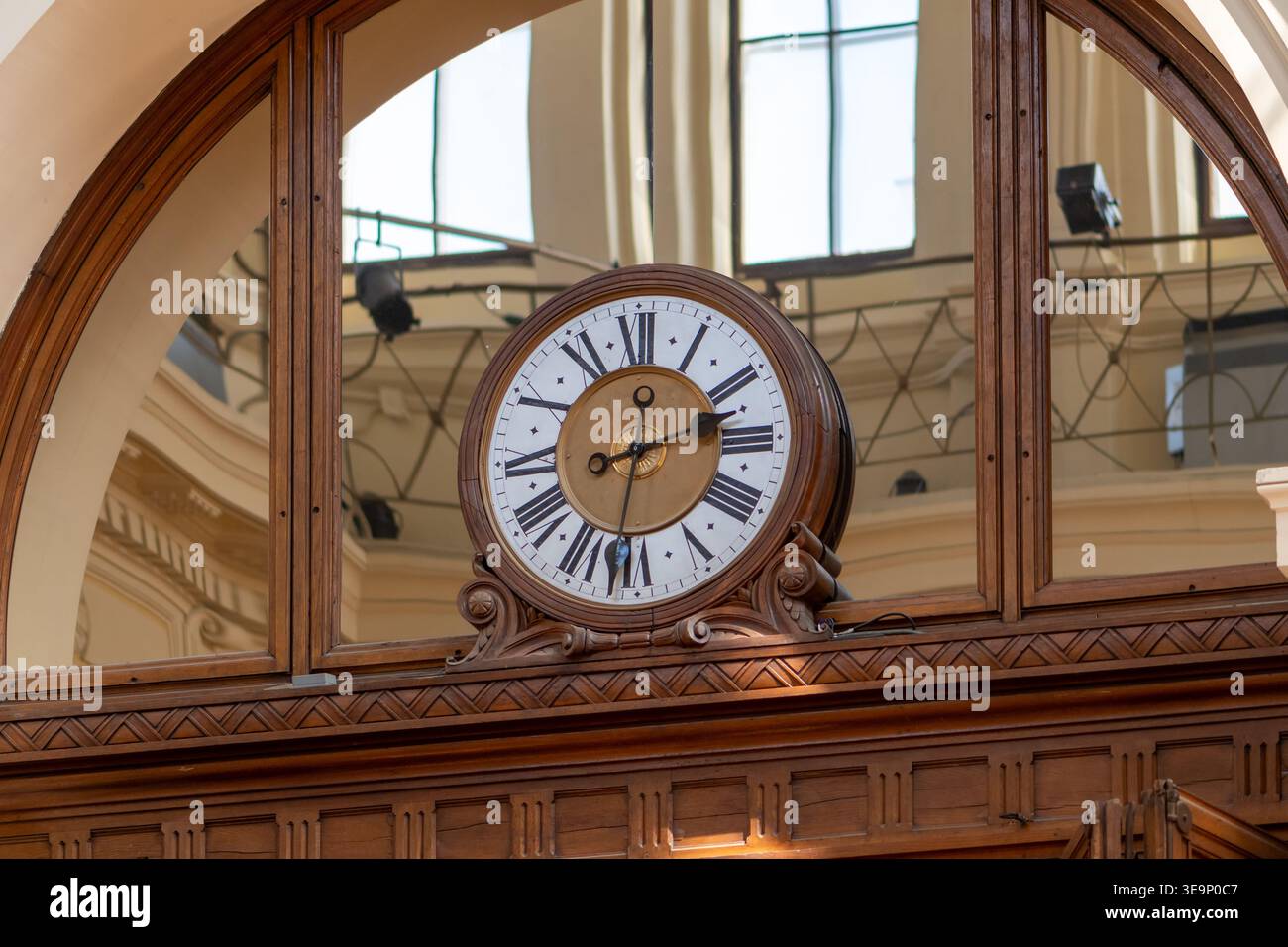 Vintage-Uhr mit römischen Ziffern im Inneren des historischen Gebäudes mit architektonischen Elementen. Stockfoto