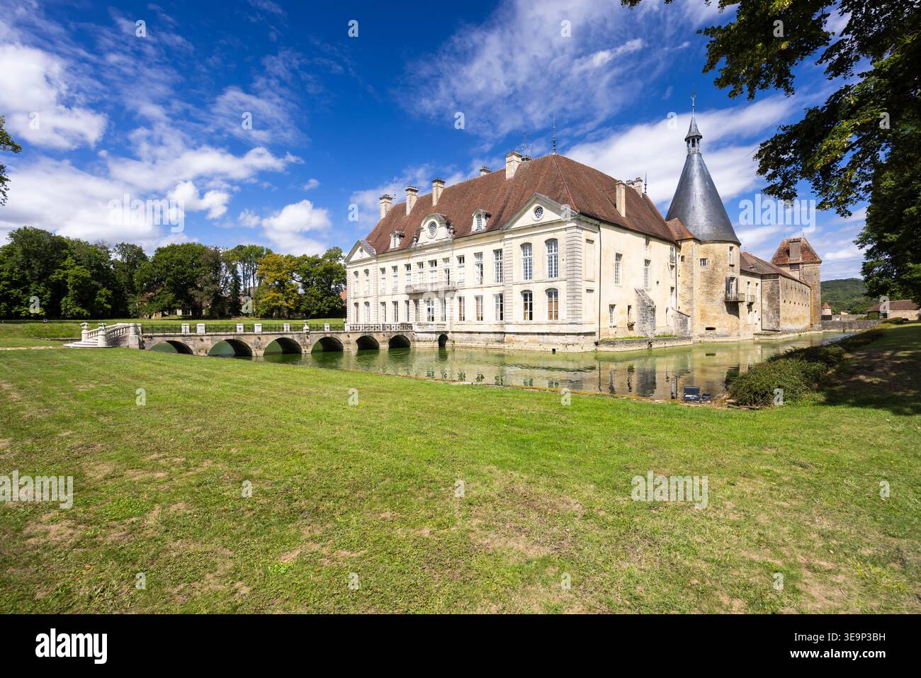 Das historische französische Schloss spiegelt sich in seinem Graben wider, umgeben von grünen Rasenflächen und Bäumen Stockfoto