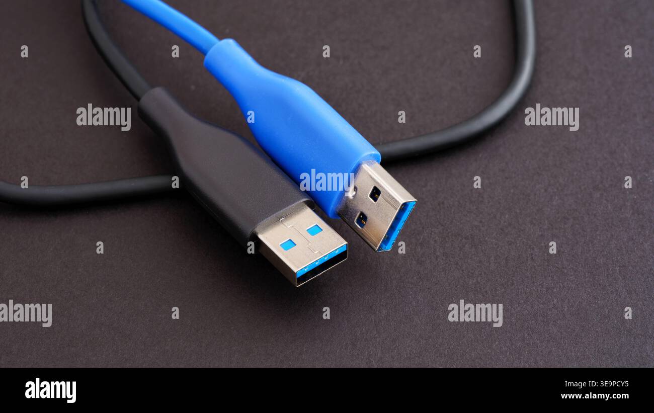 Zwei USB 3,0 Typ-A-Kabel in Schwarz und Blau auf einer dunklen strukturierten Oberfläche. Nahaufnahme. Stockfoto