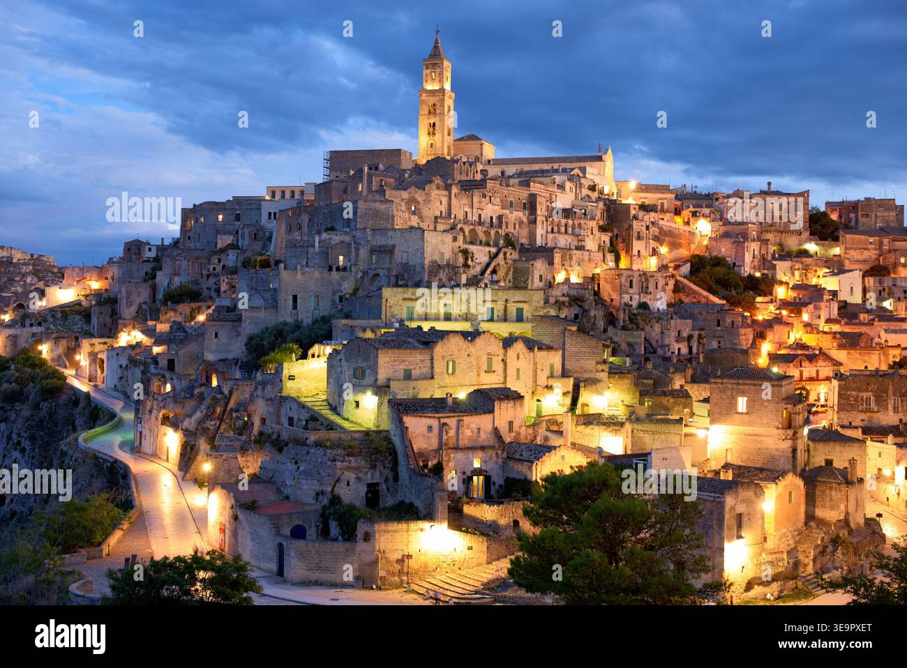Matera zeigt seine alten Steine und Gebäude, während die Lichter in der Abenddämmerung hell leuchten. Diese Szene fängt die einzigartige Architektur und Geschichte ein. Stockfoto