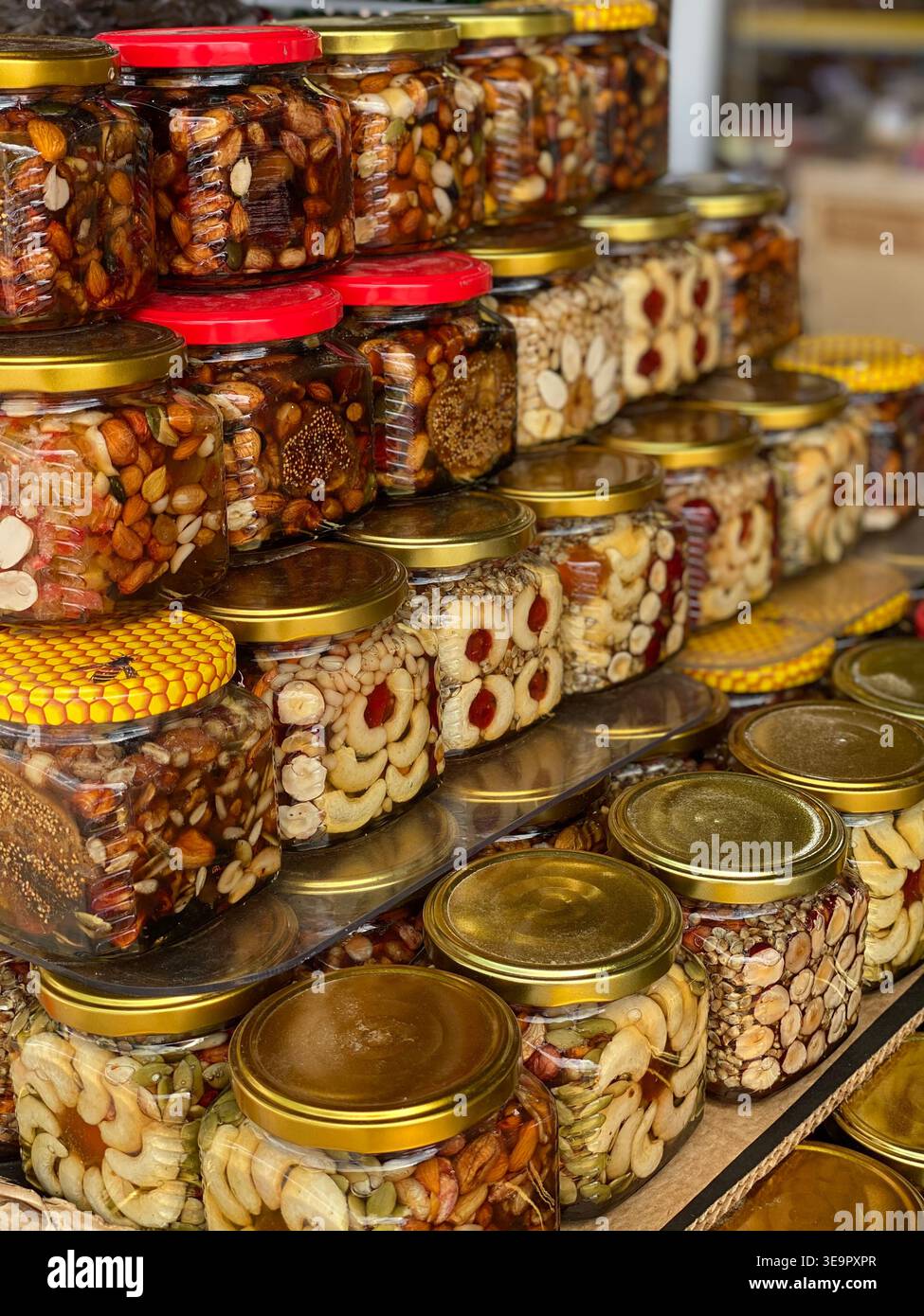 Glasgläser gefüllt mit gemischten Nüssen und Honig, ausgestellt am lokalen Marktstand - Smartphone-aufgenommenes Stockfoto