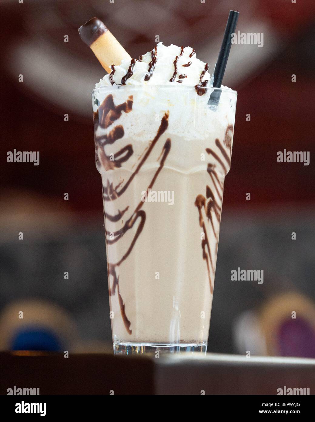 Schokoladen-Tropfen auf einem cremigen Milchshake. Schlagsahne krönt das Getränk mit einer zarten Note. Die Keksgarnitur sorgt für einen süßen Kontrast zum Stockfoto
