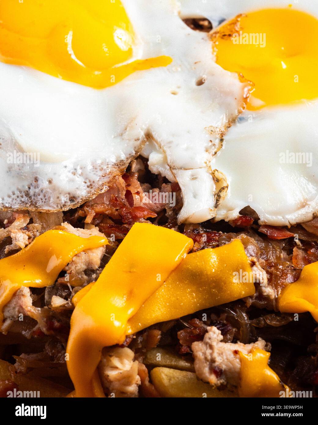 Goldenes Eigelb glänzt über knusprigem weiß. Käsige Streifen bespritzen über herzhaftes, herzhaftes Hasch. Der Texturkontrast zieht den Blick auf den Reichtum. Perfekt zum Brunch Stockfoto