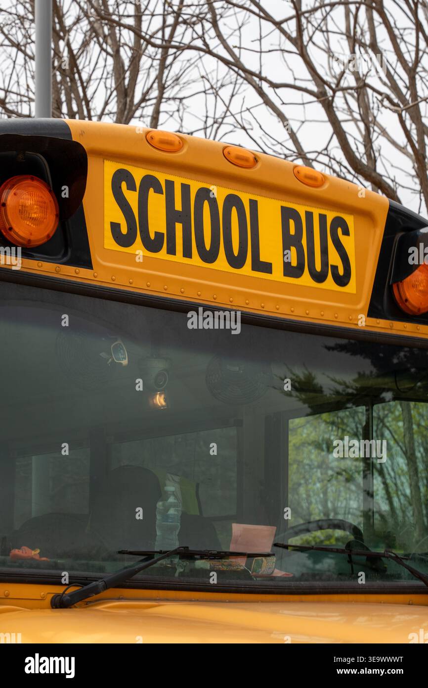 Vertikale Nahaufnahme des auffälligen „SCHOOL BUS“-Schriftstücks an der Seite eines ikonischen gelben Schulbusses, ein vertrauter Anblick, der den sicheren Transport gewährleistet Stockfoto