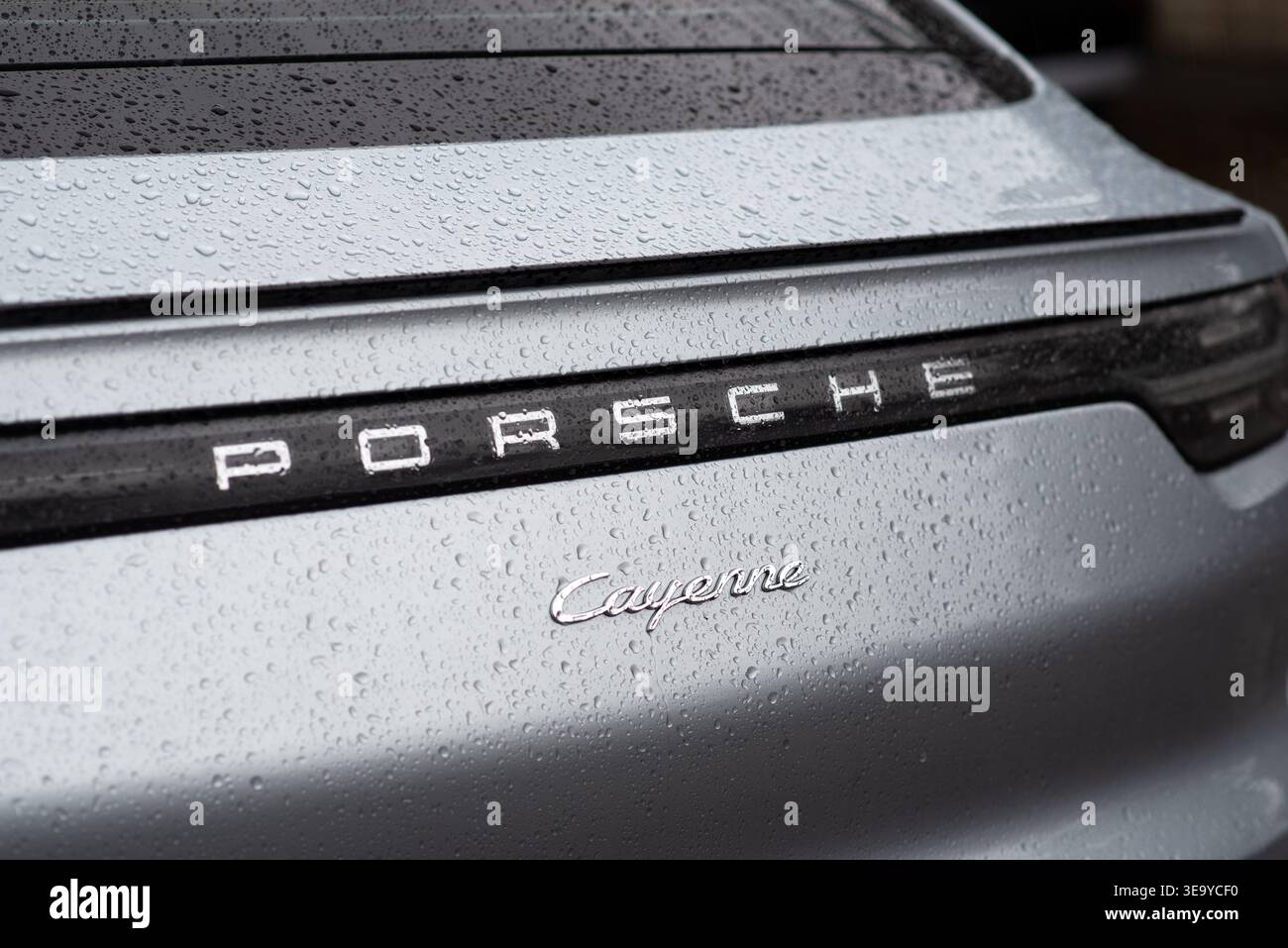 Kiew, Ukraine - März 2025. Nahaufnahme eines Porsche Cayenne Heckabzeichens mit Regentropfen auf der Oberfläche. Ein luxuriöses Fahrzeugdetail, das Eleganz und Brandin betont Stockfoto