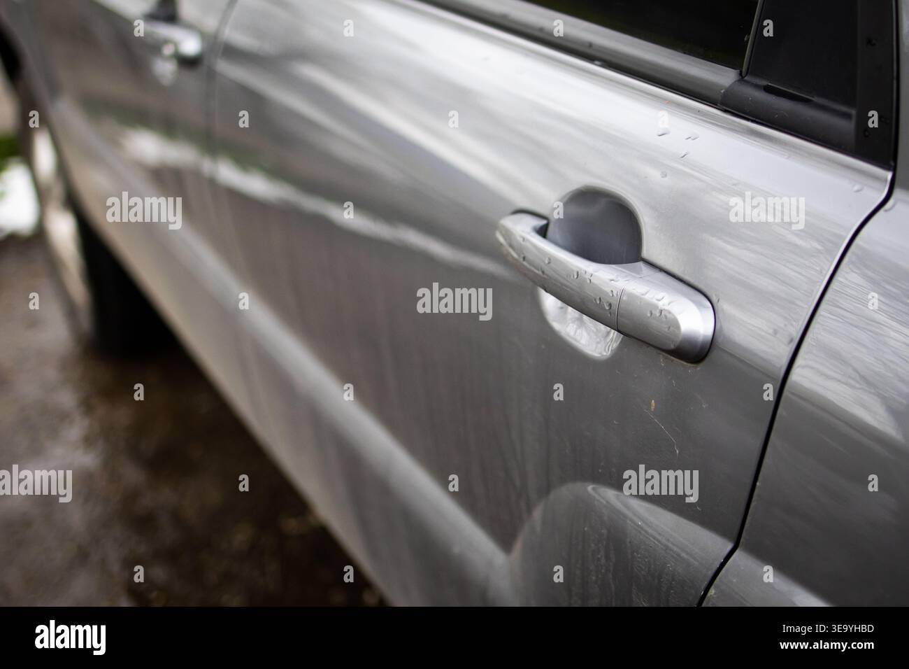 Silberner Kfz-Türgriff mit sanften Reflexionen in einem flachen Winkel. Das einfache Design im Automobilbau und die abgenutzten Streifen erzählen von der täglichen Nutzung Stockfoto