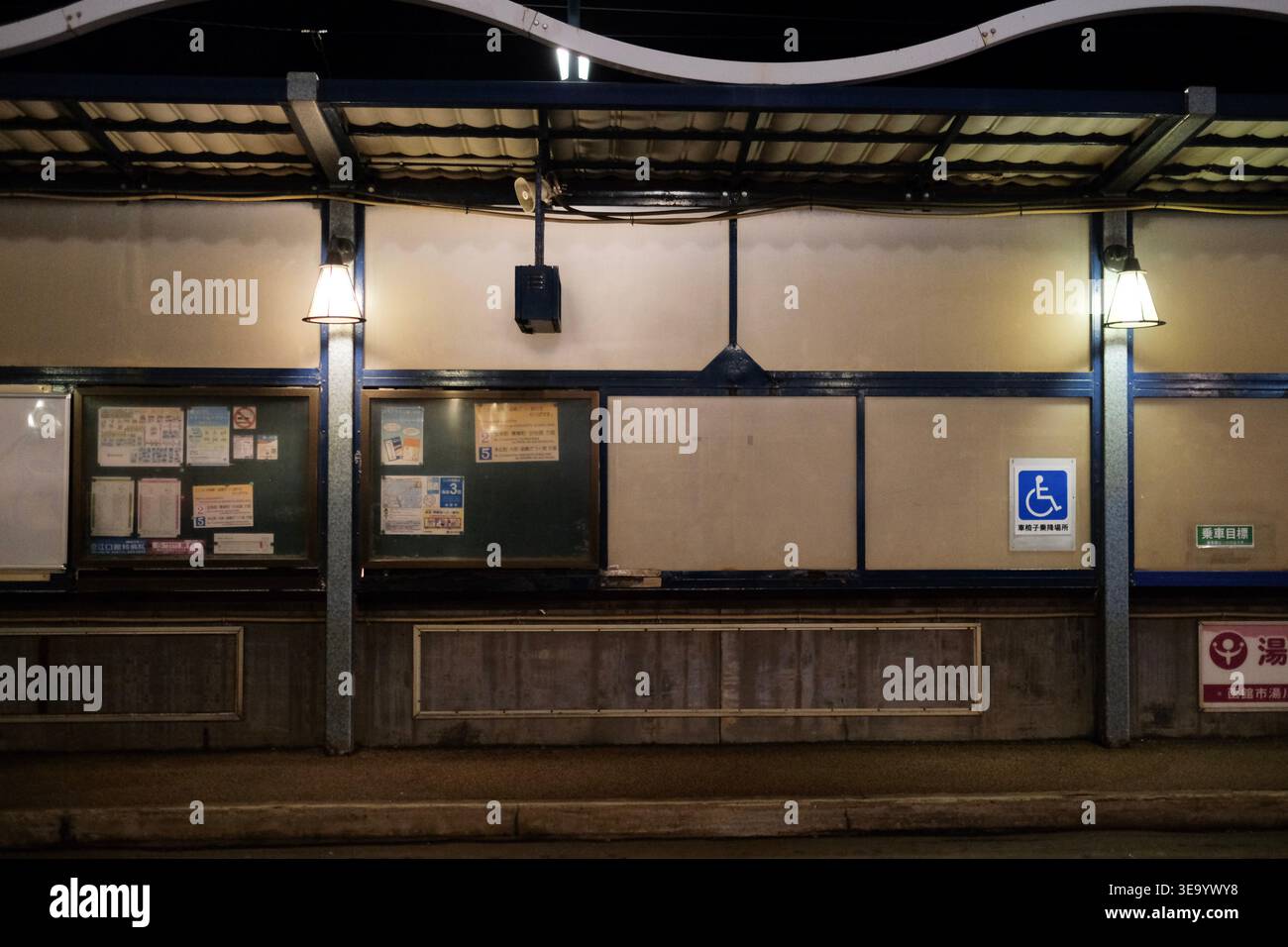 Ruhiger beleuchteter Bahnsteig bei Nacht mit Hinweistafeln und Hinweisschild Stockfoto