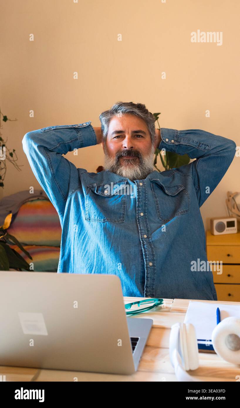 Reifer Mann, der sich am Arbeitsplatz zu Hause entspannt Stockfoto