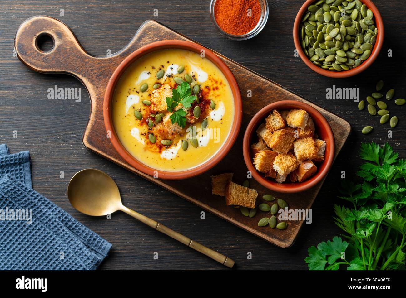 Köstliche hausgemachte Kürbiscremesuppe serviert mit knusprigen Croutons, Samen und Creme in einer rustikalen Schüssel auf hölzernem Hintergrund, Nahaufnahme. Gesunder Herbst Stockfoto