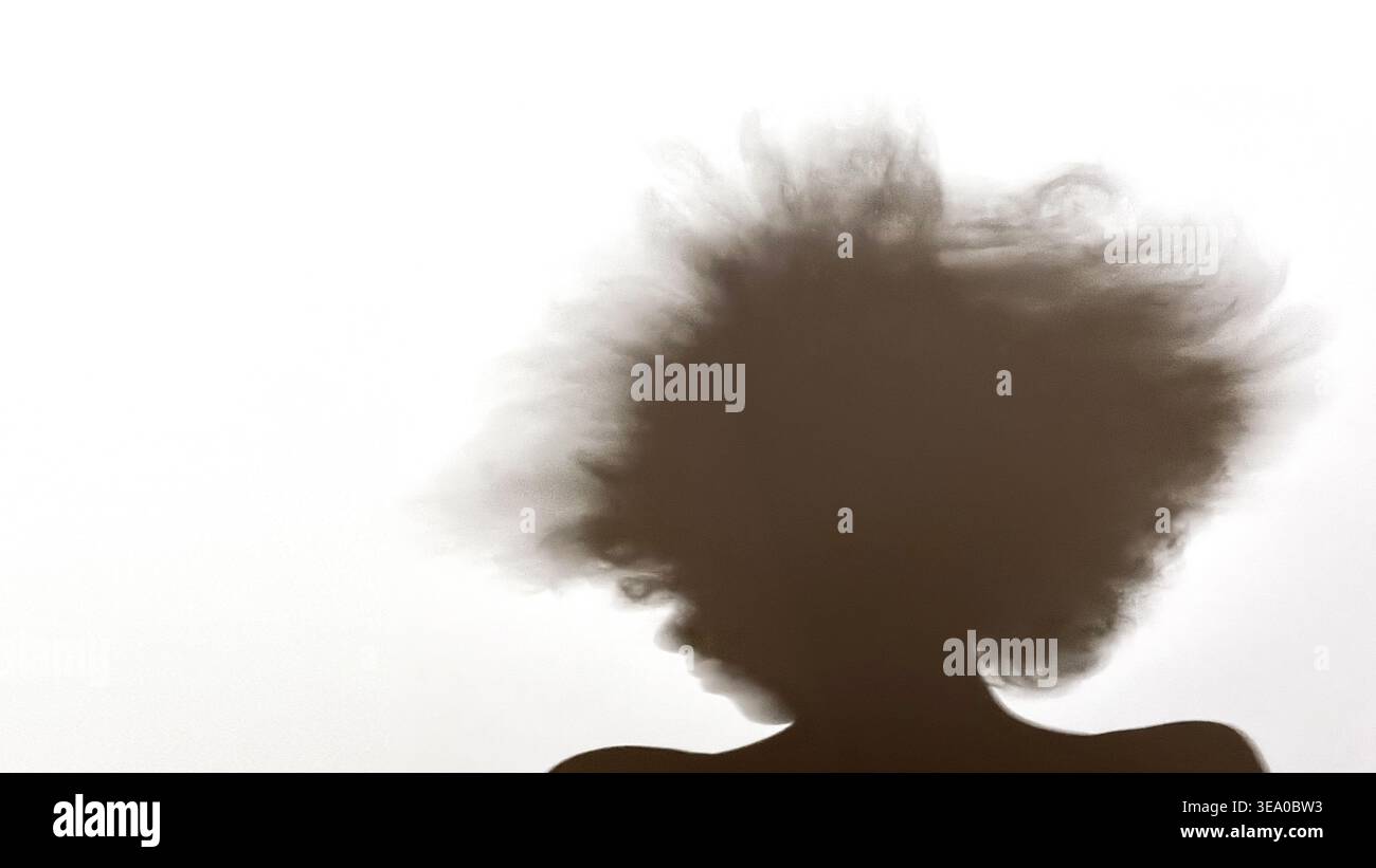 Verschwommene Teen Silhouette mit Bewegungshaar auf neutralem Hintergrund mit Kopierraum Stockfoto