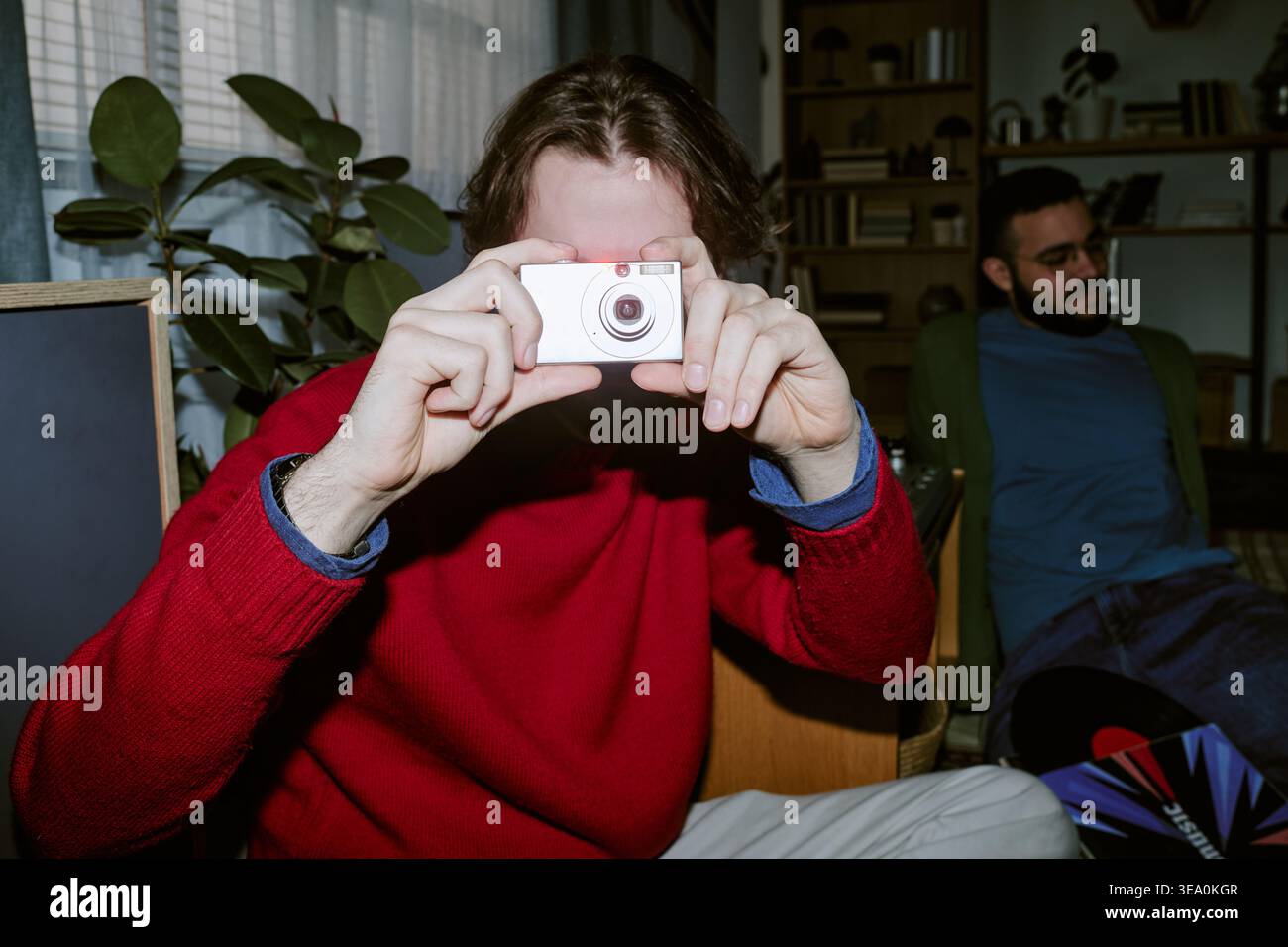 Erwachsener mit Kompaktkamera und Gelegenheitsfotos in Innenräumen Stockfoto