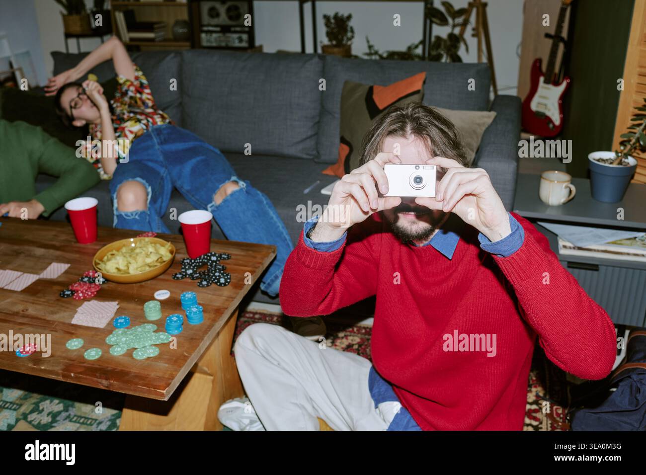 Erwachsener Mann macht Sofortfotos während der Friends Game Night zu Hause Stockfoto